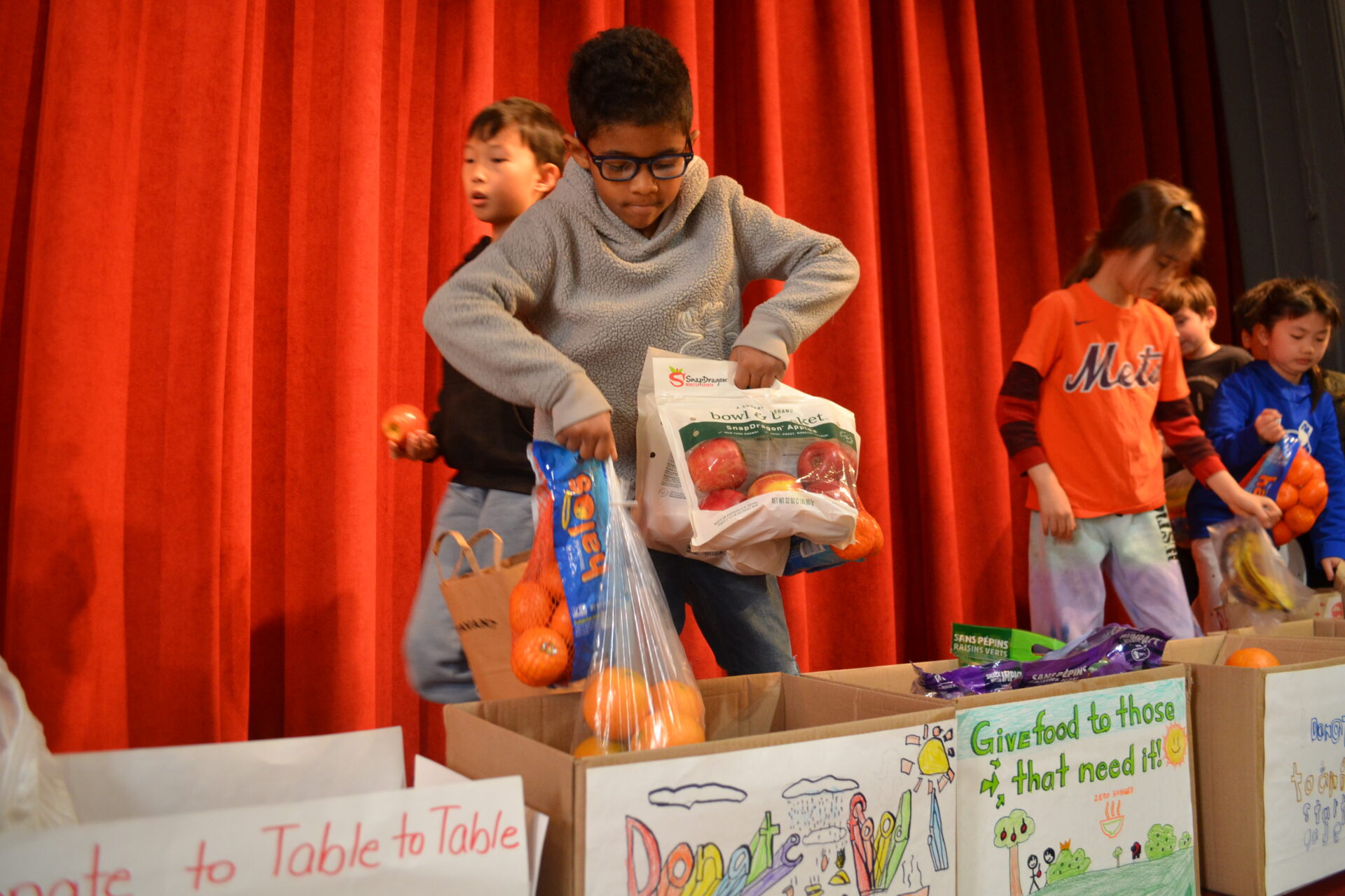 Students at Anna C. Scott Elementary School drop donations in boxes for Table to Table.