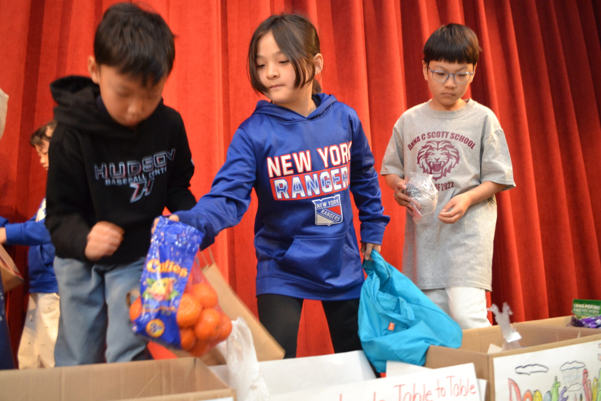 Students at Anna C. Scott Elementary School drop donations in boxes for Table to Table.